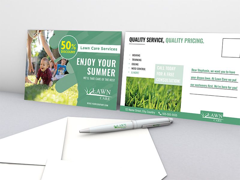Two Lawncare Business Postcards Standing Up Showing their Front and Back with a Pen and Envelope in Front of Them